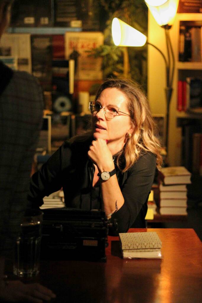 Nicola Gold, sitting in profile, talking to someone at a literary festival.
