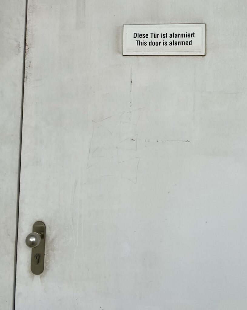 Tür mit Schild: "Diese Tür ist alarmiert. This door is alarmed."
